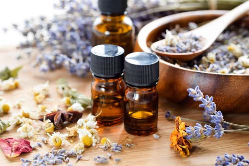 Three dark essential oil bottles with herbs around them