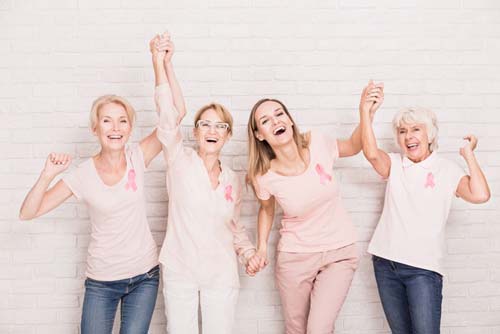 Group of ladies wearing breast cancer ribbons cheering