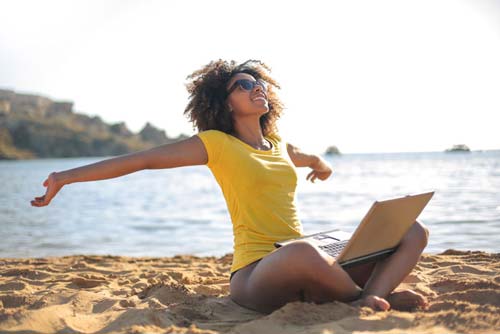 Girl relaxing at the beach with a laptop in her lap