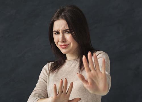 Scowling woman with her hands up showing major disinterest