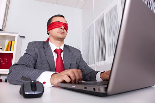 Blindfolded businessman working on laptop