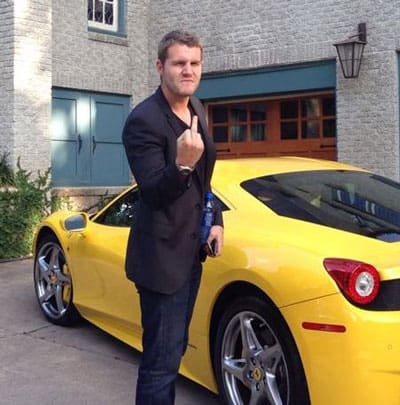 Alex Becker giving middle finger standing in front of yellow Ferrari